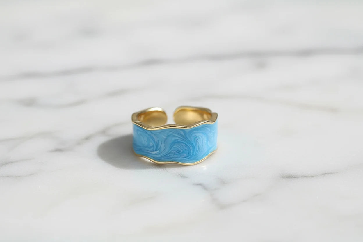 Front view of the Blue Marble Open Wave Ring on white marble surface, showing wavy blue enamel | OriaJewel