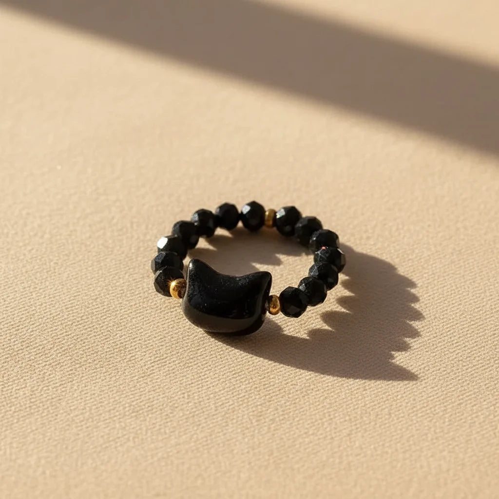 Black faceted bead Cat Charm Ring, gold accents, on sunlit beige | Oria Jewel