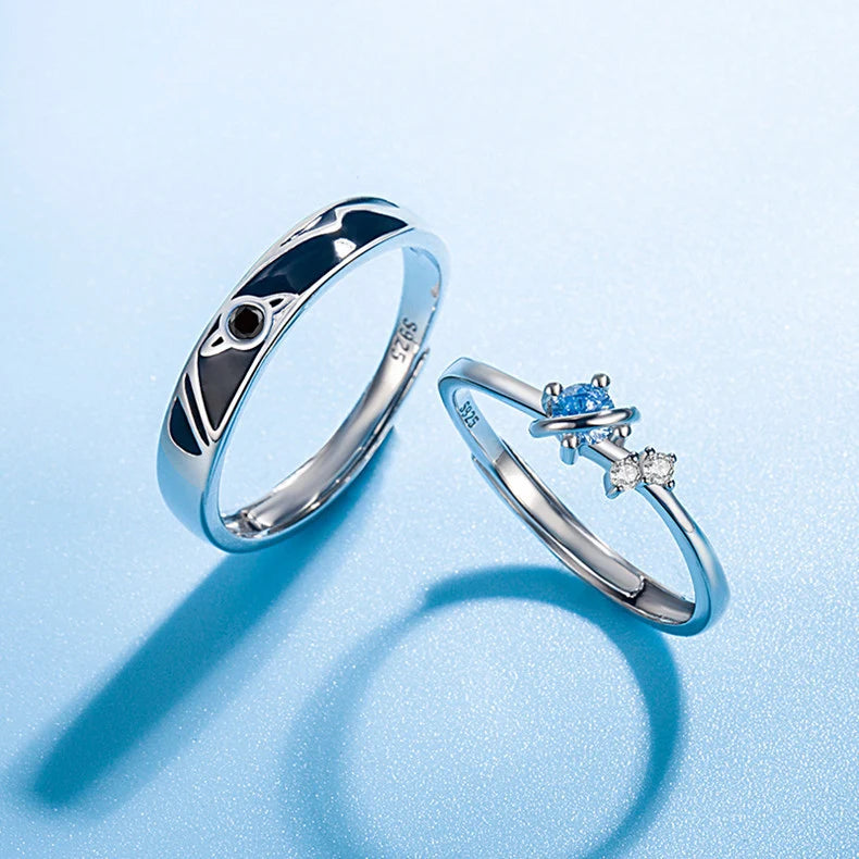 Cosmic Heart Couple Ring pair arranged on a blue background with soft shadows, highlighting the matching couple design—cosmic enamel band and blue heart crystal ring—side by side | OriaJewel