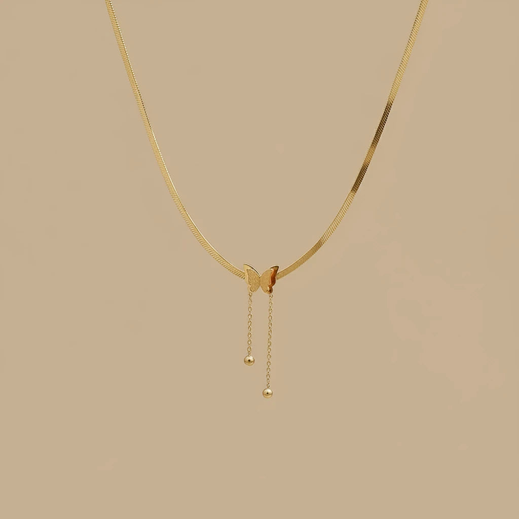 Minimalist Gold Butterfly Chain Necklace with butterfly pendant and drop chains on beige background | Oria Jewel