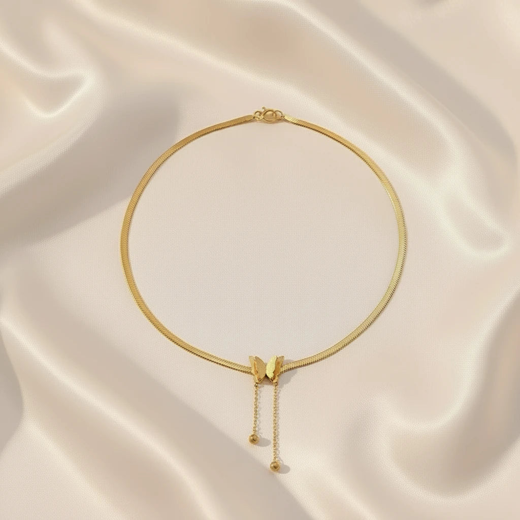 Gold Butterfly Chain Necklace elegantly arranged on soft satin background under warm light | Oria Jewel