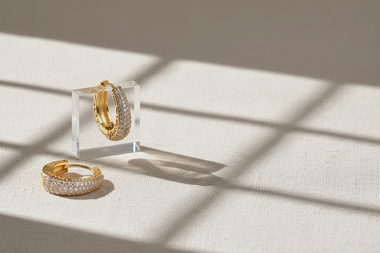 Gold Pavé Huggie Hoop Earrings on acrylic stand with window shadows | OriaJewel