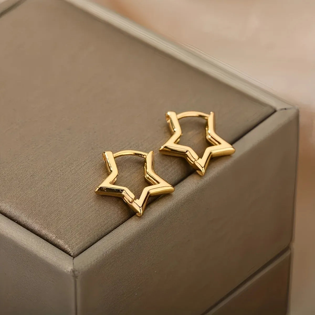 Gold Star Huggie Hoop Earrings close-up on jewelry box cushion | OriaJewel