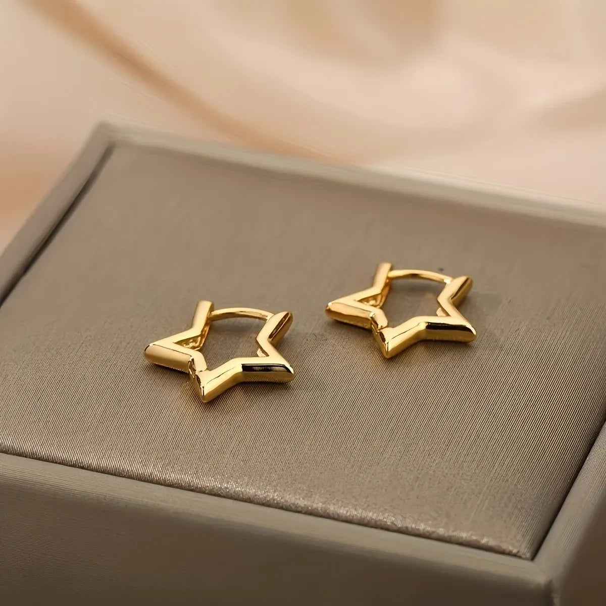 Gold Star Huggie Hoop Earrings close-up pair on jewelry box | OriaJewel