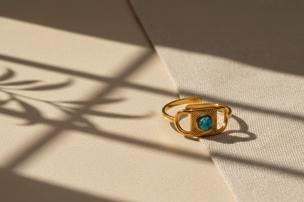 Gold Turquoise Adjustable Open Ring styled on fabric under window-grid shadows, emphasizing the gold geometric frame, sunburst texture, and turquoise center stone in natural light | OriaJewel