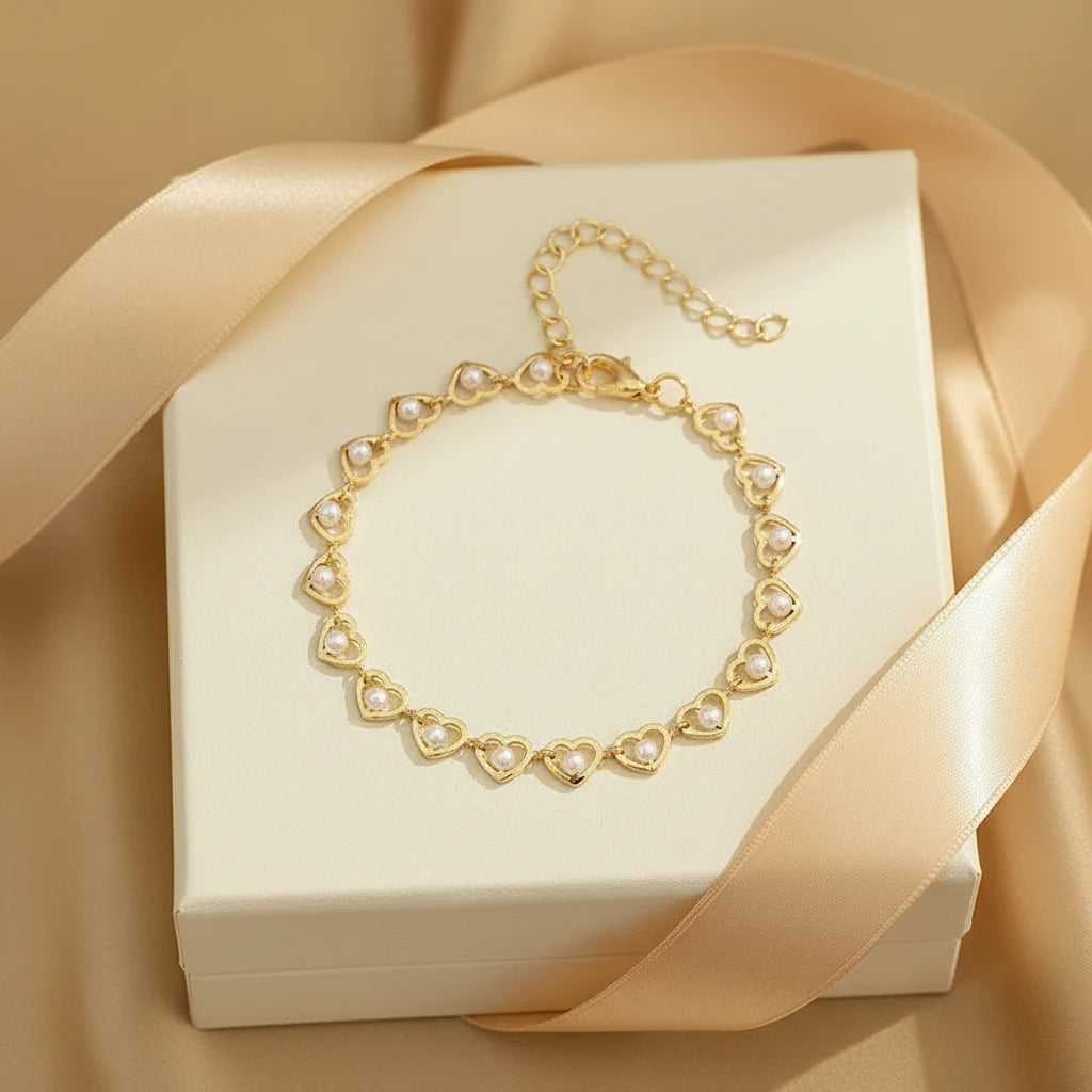 Gift-ready presentation of the Golden Pearl Heart Chain Bracelet styled on top of a cream jewelry box with satin ribbon, the heart-shaped links and pearls creating a romantic, feminine feel | Oria Jewel