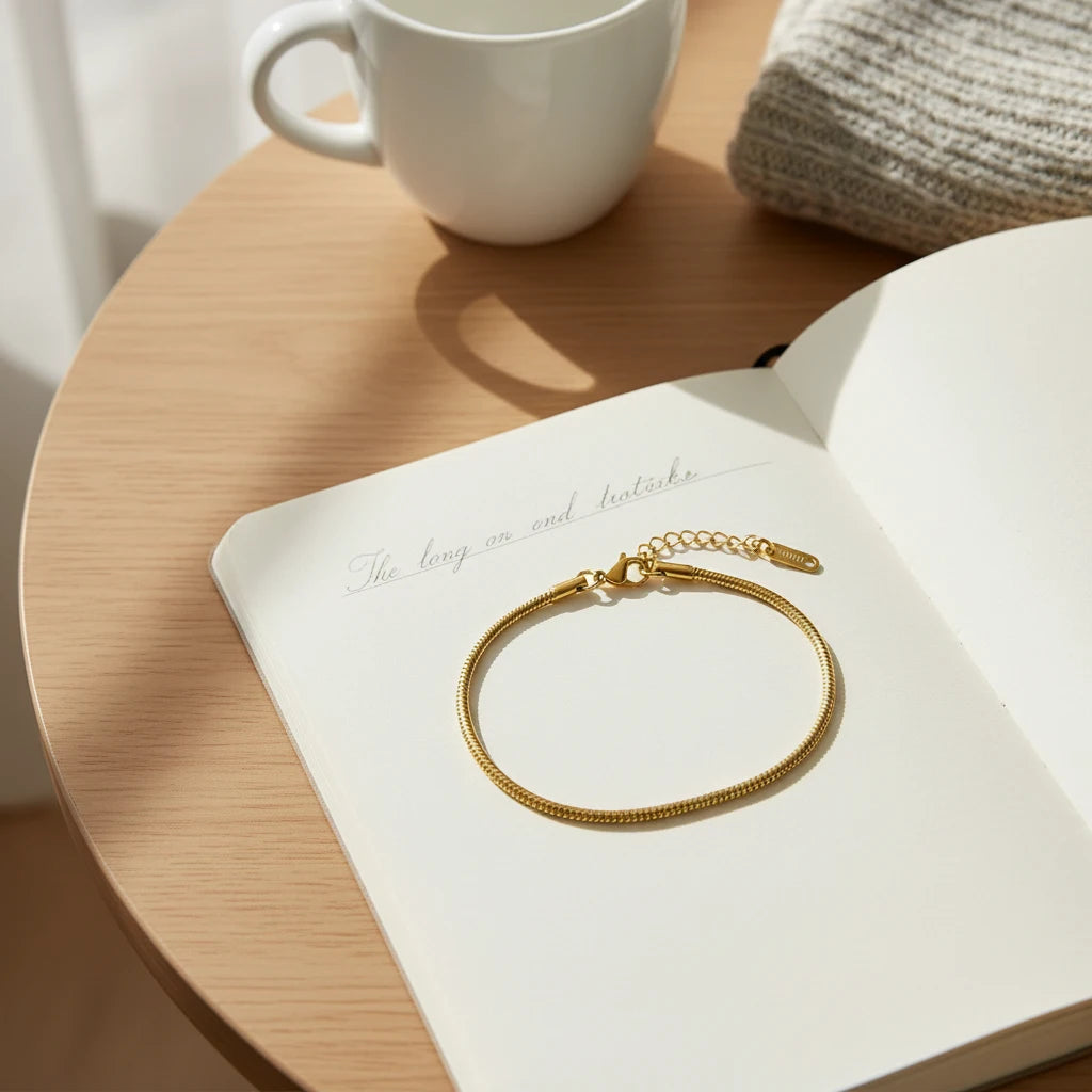 Minimalist Gold Chain Bracelet resting on an open notebook beside a white coffee mug in morning sunlight | Oria Jewel