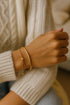 Hand wearing a gold bracelet with a blurred background