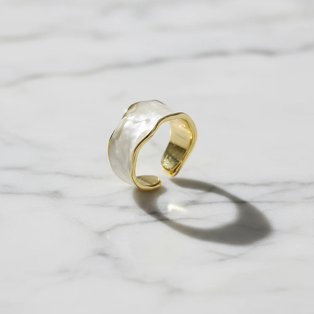Pearl White Open Wave Ring standing on a light marble background with a soft shadow, showing the open cuff fit, curved wave top edge, and reflective gold-toned inside | OriaJewel