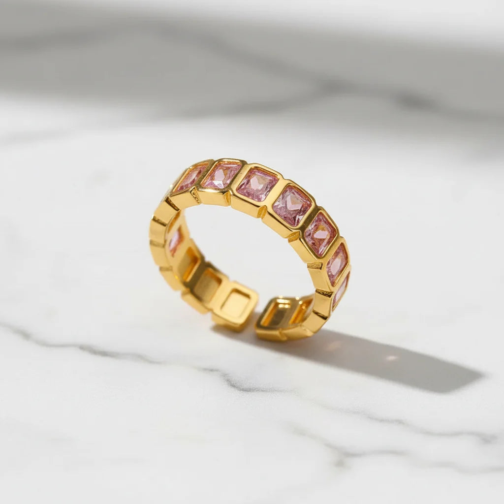 Rose stone band ring close-up on white marble surface, gold band with pink stones in crisp focus | OriaJewel