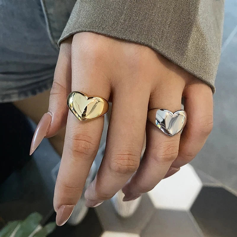 Close-up: hand wearing shiny gold and silver Modern Love Heart Rings | Oria Jewel