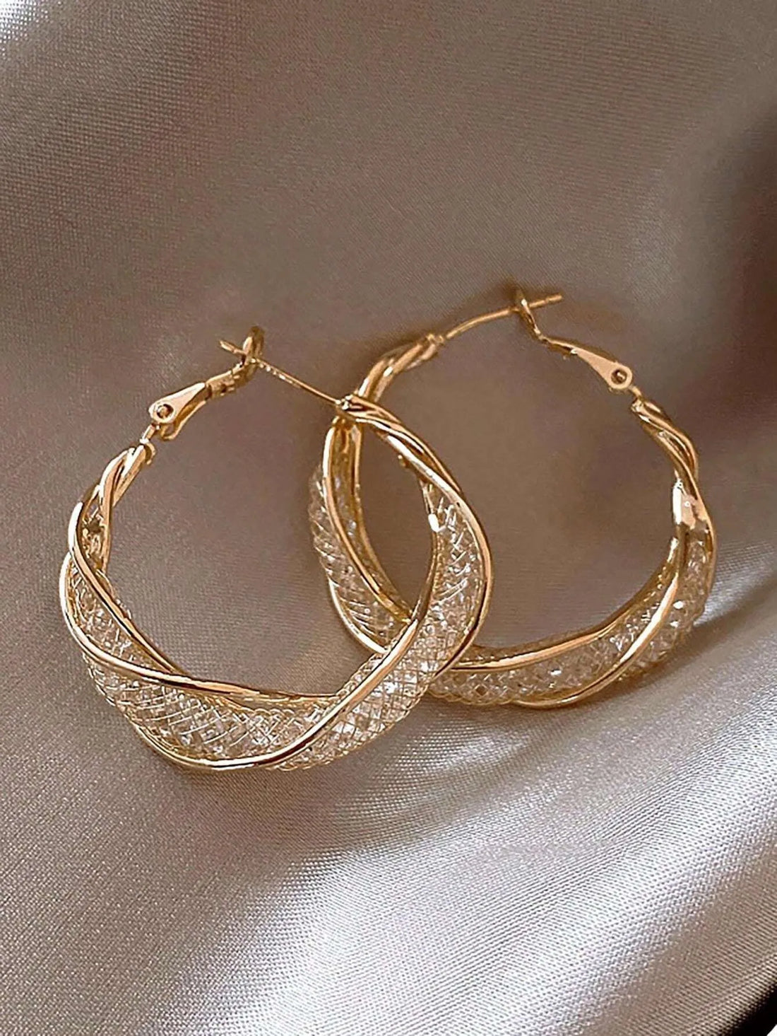 Two sparkling gold hoop daisy earrings on soft taupe silk | Oria Jewel