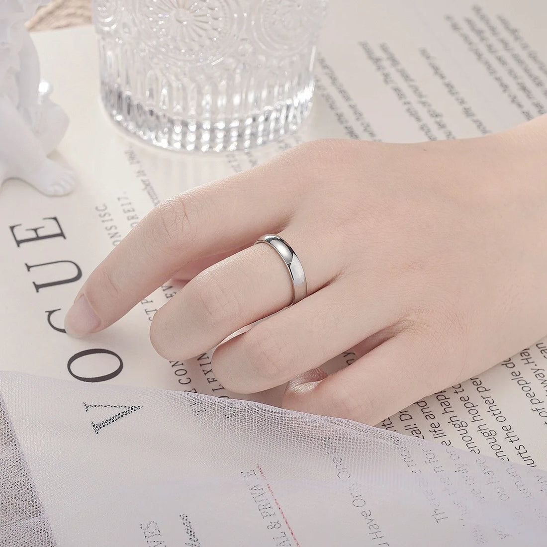 Elegant hand showcases a gleaming Classic Silver Band Ring on a magazine | Oria Jewel