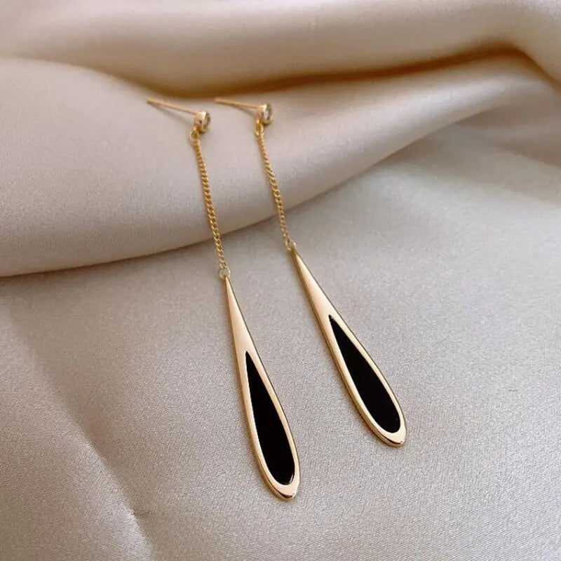 Elegant gold Teardrop Chain Earrings with black accents, displayed on soft cream silk | Oria Jewel