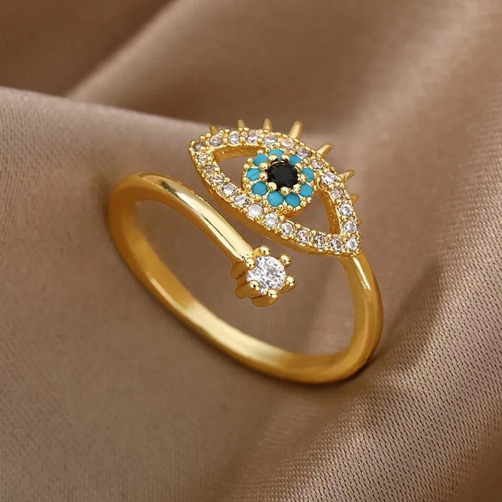 Close-up of a gold adjustable Blue Crystal Evil Rings with clear accents on soft fabric | Oria Jewel