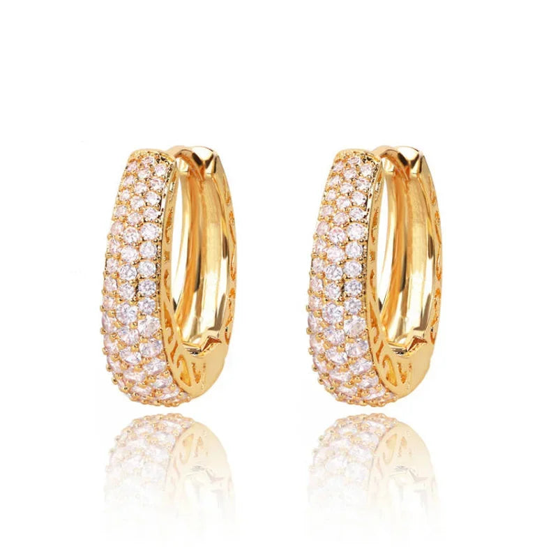 Two sparkling Crystal Gold Huggie Earrings on a reflective white surface | Oria Jewel