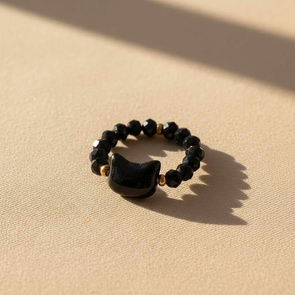 Black faceted bead Cat Charm Ring, gold accents, on sunlit beige | Oria Jewel