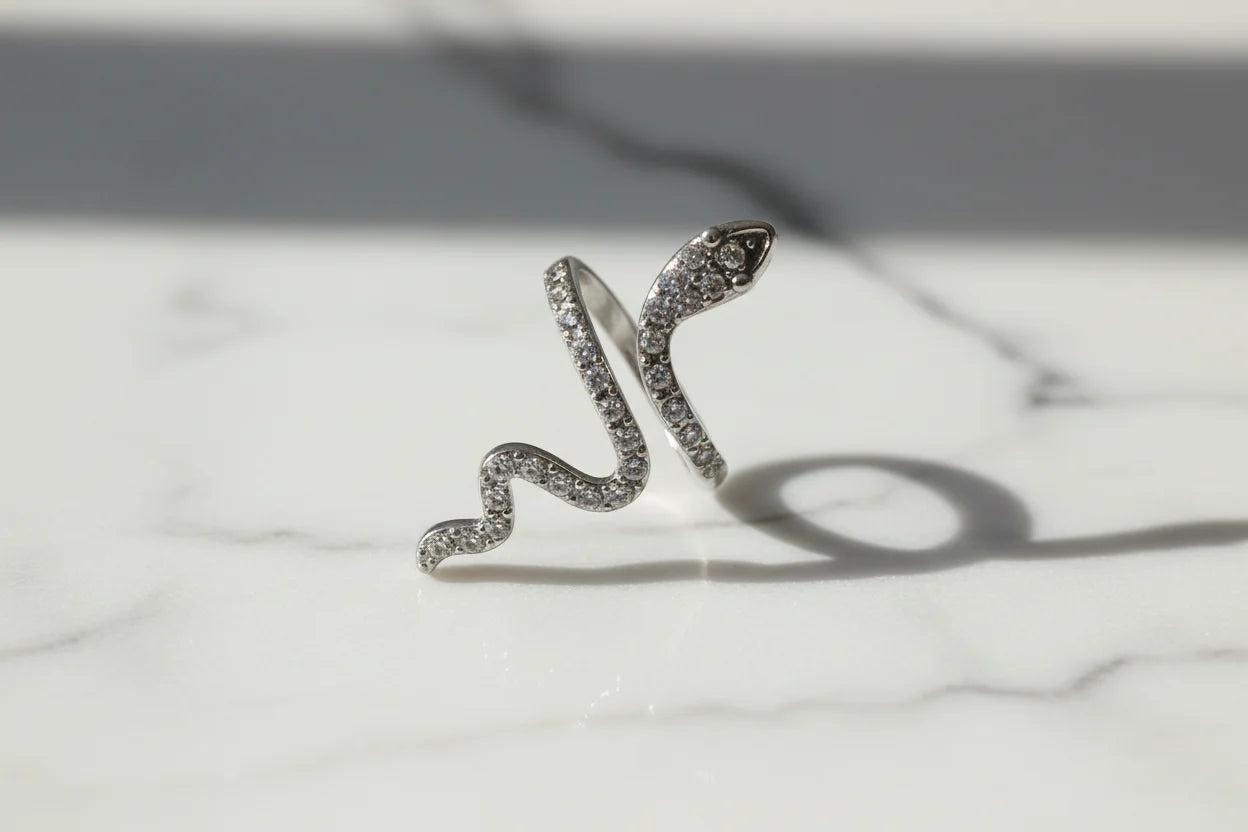 Silver Pavé Snake Wrap Ring macro on a white marble surface with soft natural reflections, detailed view of the pavé-set snake head and winding band | OriaJewel
