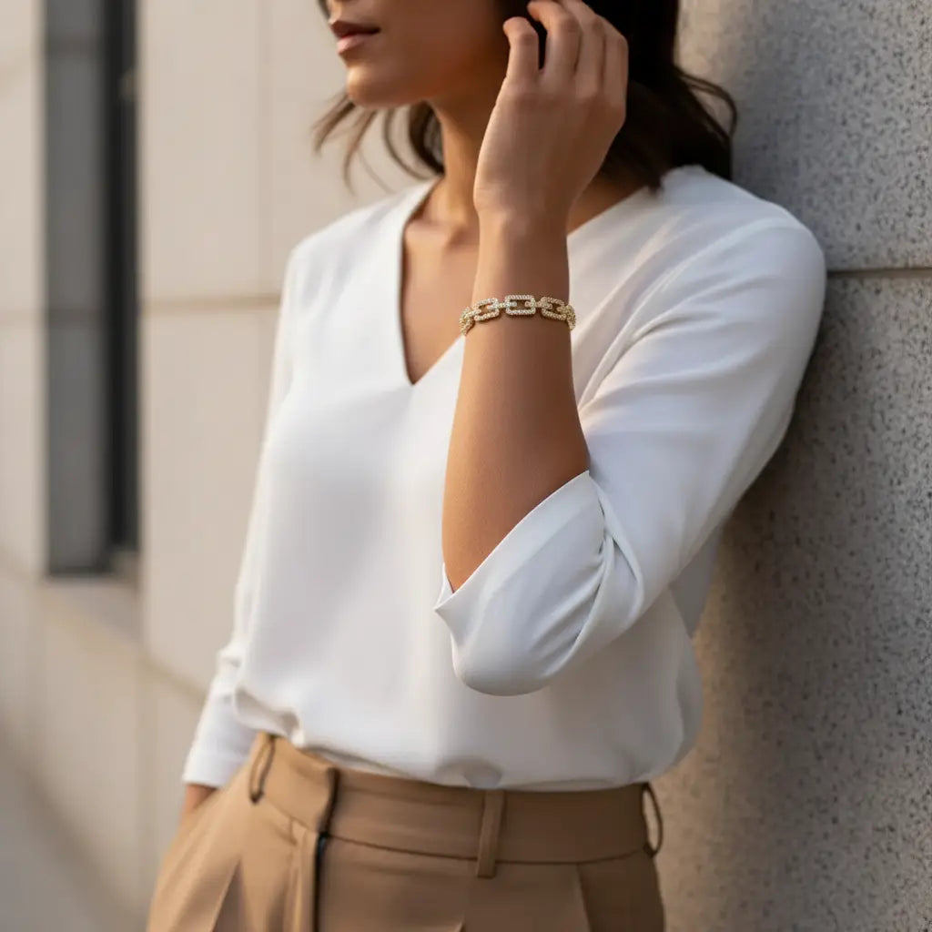 Close-up of woman in a white blouse and tailored trousers leaning against a wall, highlighting the Veluxa Pavé Link Cuff as a chic workday accessory | Oria Jewel