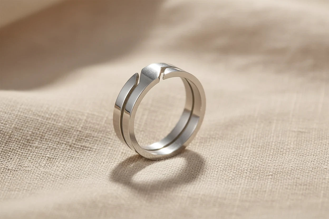 Wide Silver Band Ring close-up on textured beige fabric, showing the bold wide profile, clean silver shine, and angular stepped detail under warm natural light | OriaJewel