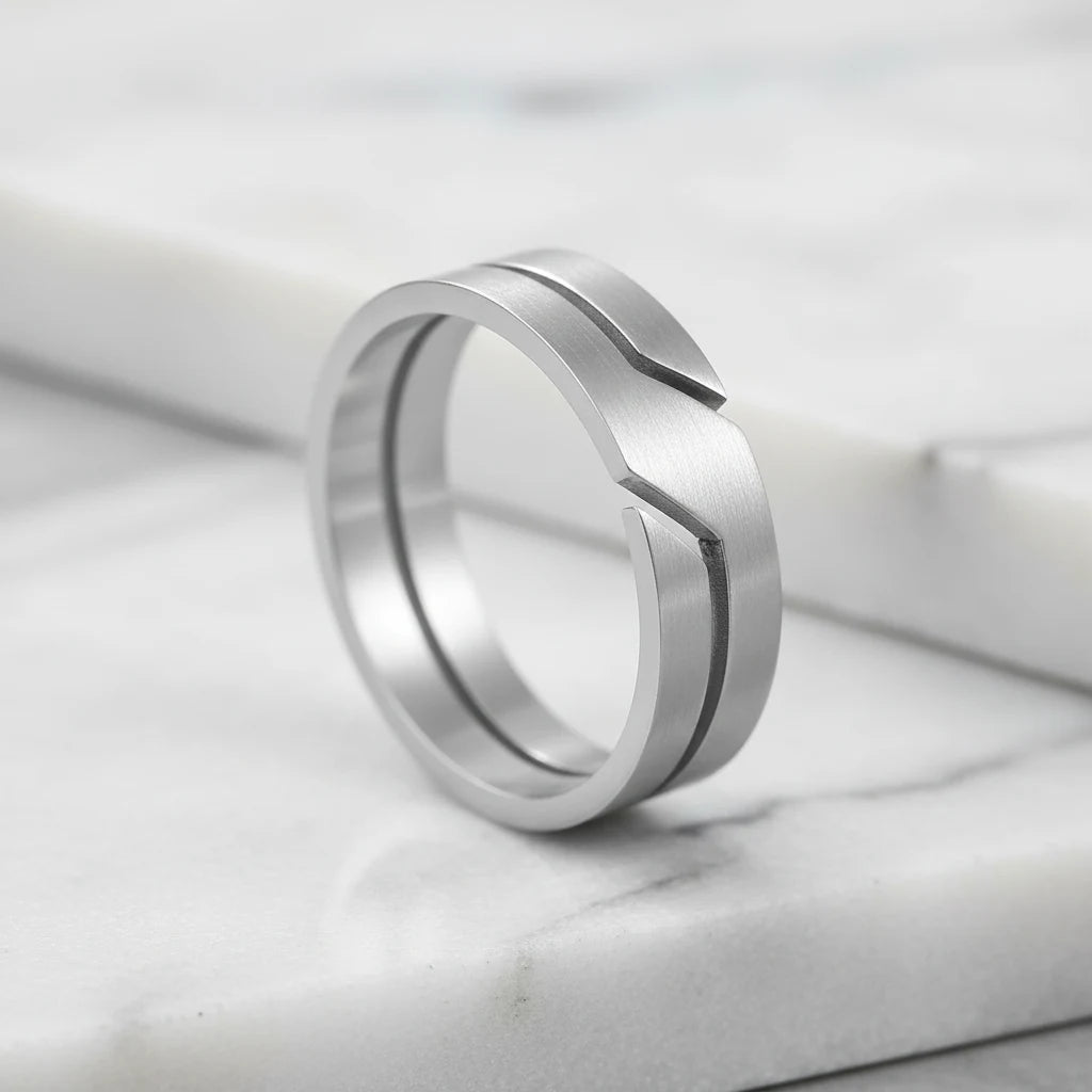 Wide Silver Band Ring macro shot on a white marble surface, focusing on the brushed-silver look, sharp modern groove line, and thick band shape with soft highlights | OriaJewel
