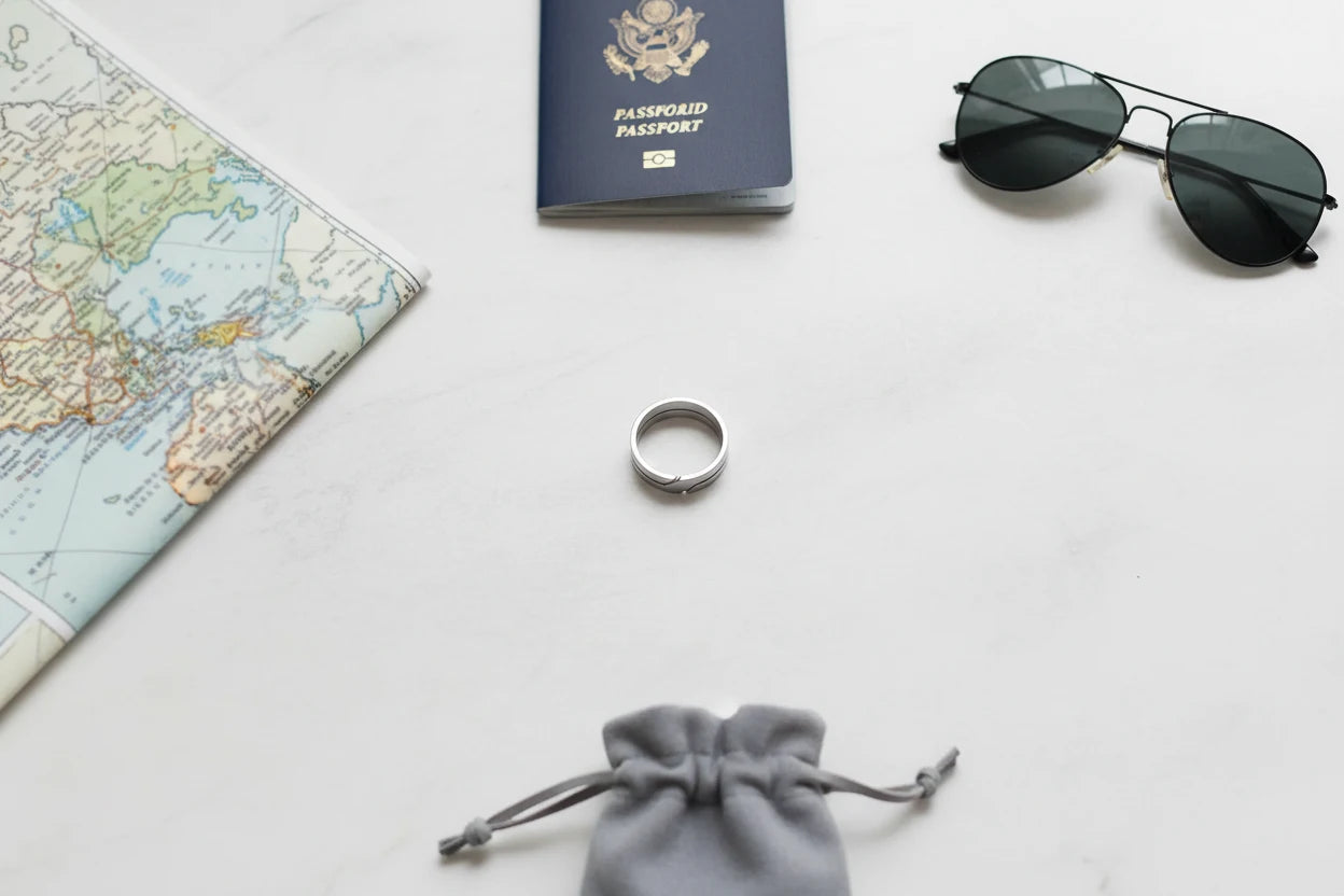 Wide Silver Band Ring styled in a travel flat lay with a passport, sunglasses, folded map, and a gray jewelry pouch, centered on a bright clean background to spotlight the wide silver band design | OriaJewel