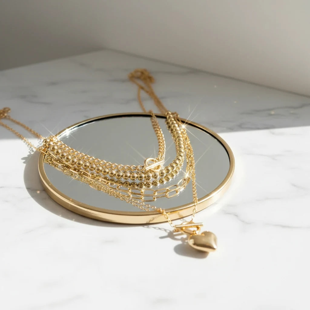 Y2K Heart Layered Necklace in gold arranged on round mirror reflecting light for elegant jewelry display | Oria Jewel