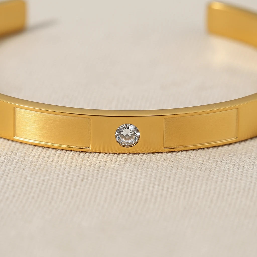 Macro detail of the gold crystal cuff bracelet showing a single round crystal set between brushed rectangular panels, emphasizing texture and shine | Oria Jewel