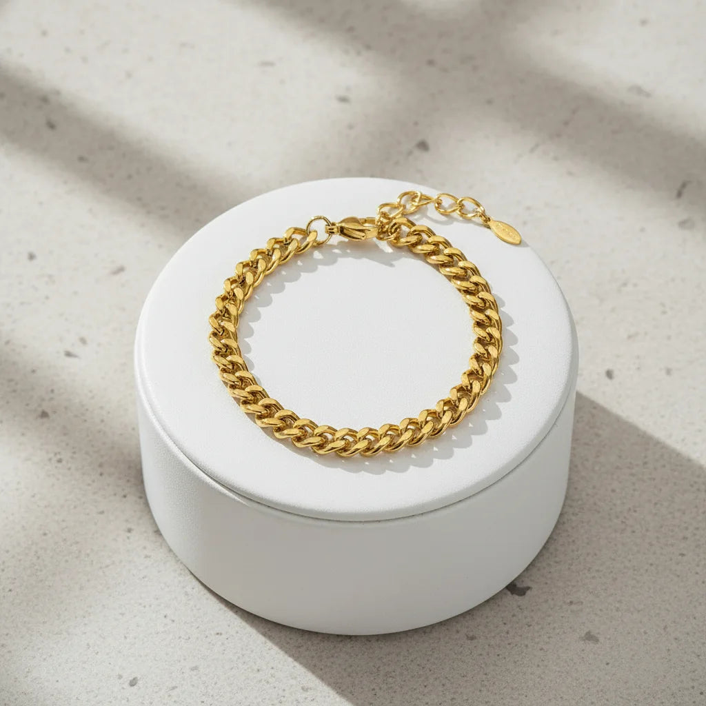 Minimal gold curb chain bracelet showcased on a round white jewelry box with soft natural light and subtle shadows | Oria Jewel