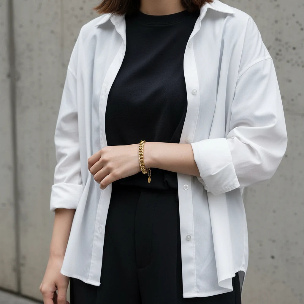 Street-style outfit featuring a woman wearing a gold curb chain bracelet with black top and white shirt for everyday layering | Oria Jewel