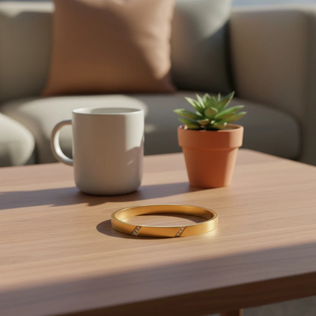 Cozy living room scene with a gold hinged bangle bracelet resting on a wooden coffee table beside a white mug and a small potted succulent, soft afternoon light creating gentle shadows, gold hinged bangle bracelet | Oria Jewel