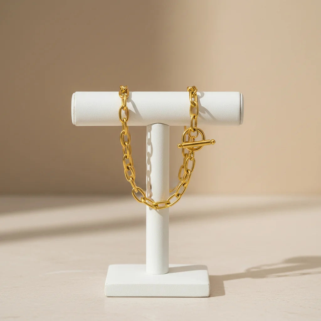 Elegant display of oval link chain bracelet draped over a modern white T-bar jewelry stand against a soft beige backdrop | Oria Jewel