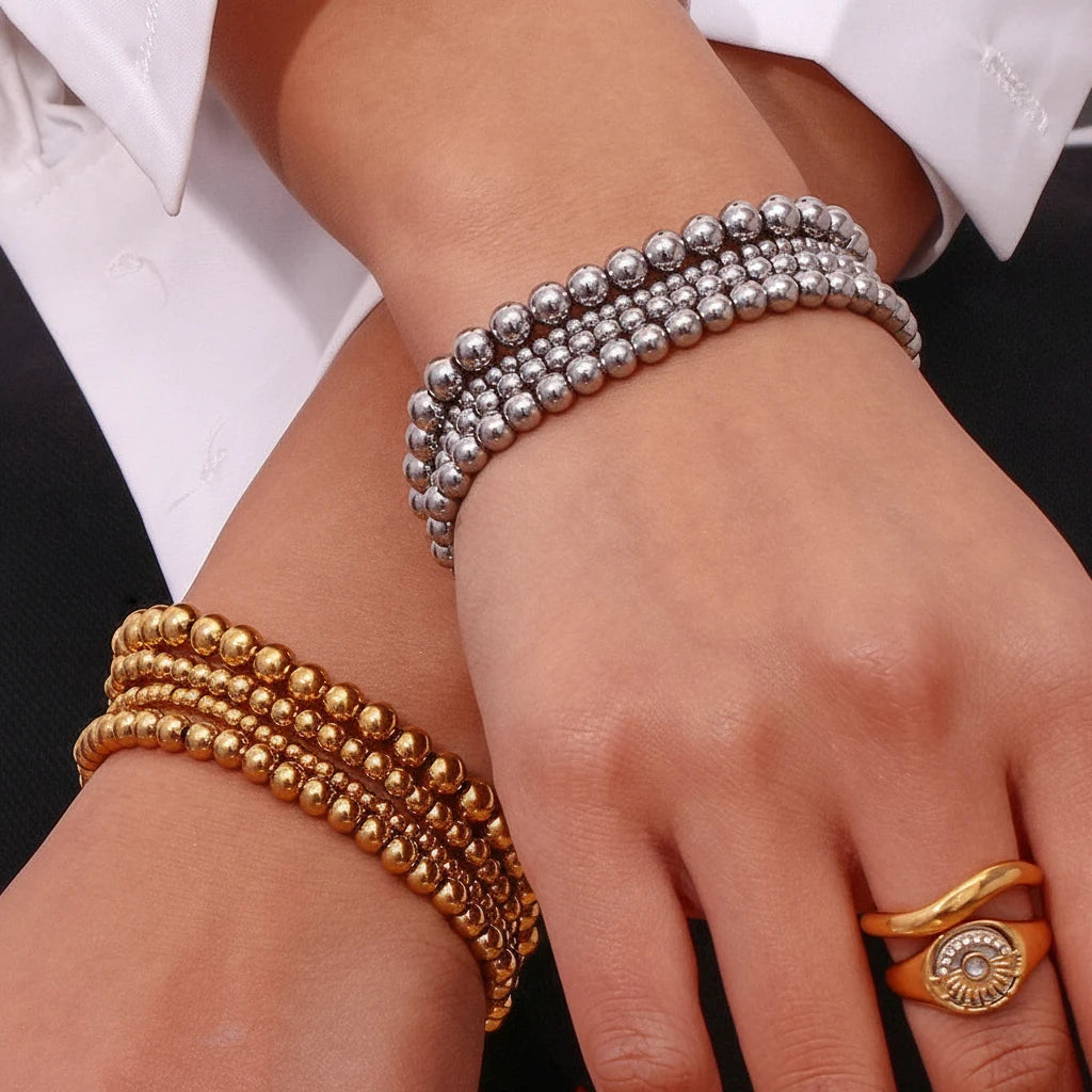 Close-up of stacked wrists showing mixed metal styling, with multiple rows of the Silver Beaded Stretch Bracelet layered beside gold beaded bangles and statement rings | Oria Jewel