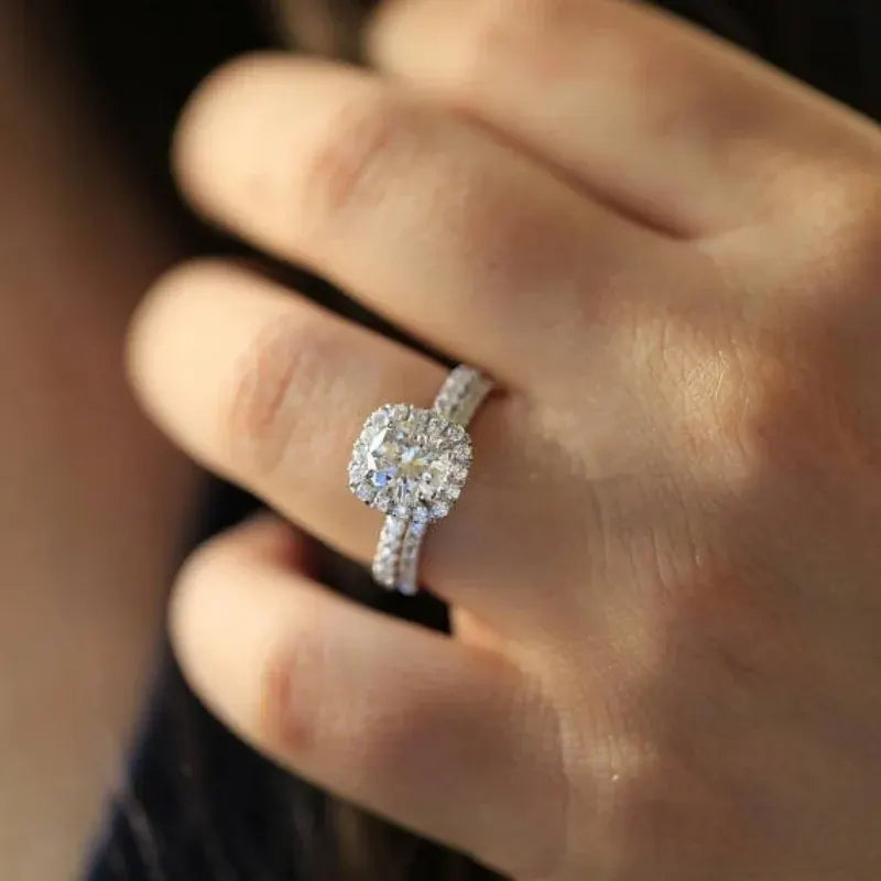 Soft Shine Halo Ring worn on a hand, featuring a round center stone with a sparkling halo frame and a double pavé band, shot in warm natural light with a soft blurred background | OriaJewel