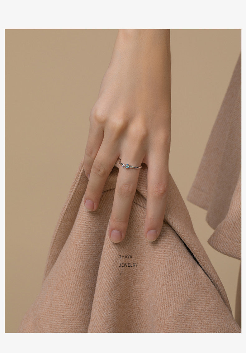 Close-up of a hand wearing a stylish silver ring, holding a soft beige cloth.