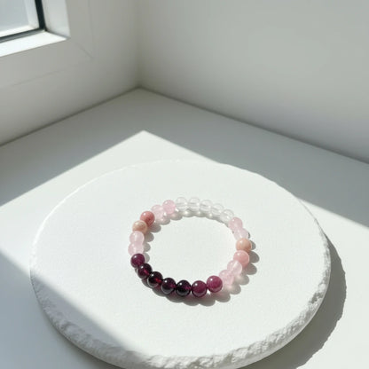 Minimalist shot of the Aurora Healing Crystal Bracelet on a round white pedestal by a bright window, showcasing its pastel gemstone tones | Oria Jewel