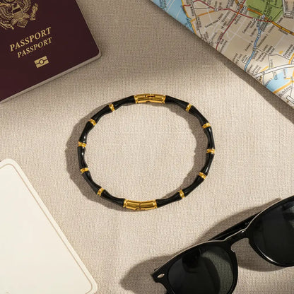 Flat lay of Black Bamboo bangle Bracelet arranged with passport, city map, and black sunglasses, styled as an elegant travel accessory in natural light | Oria Jewel
