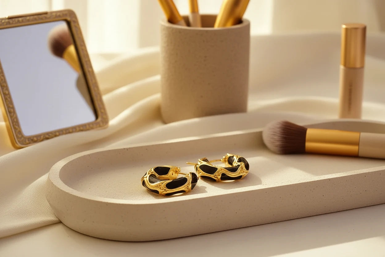 Black Huggie Hoop Earrings on vanity tray with makeup brushes in sunlight | OriaJewel