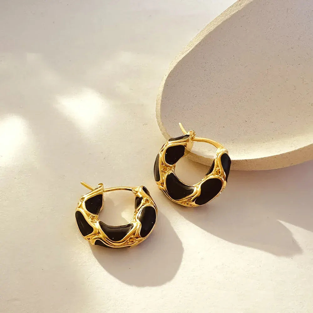 Black Huggie Hoop Earrings close-up on white surface with ceramic dish | OriaJewel