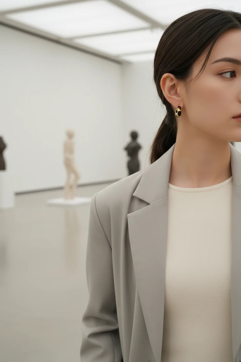 Black Huggie Hoop Earrings worn by model in modern gallery setting | OriaJewel