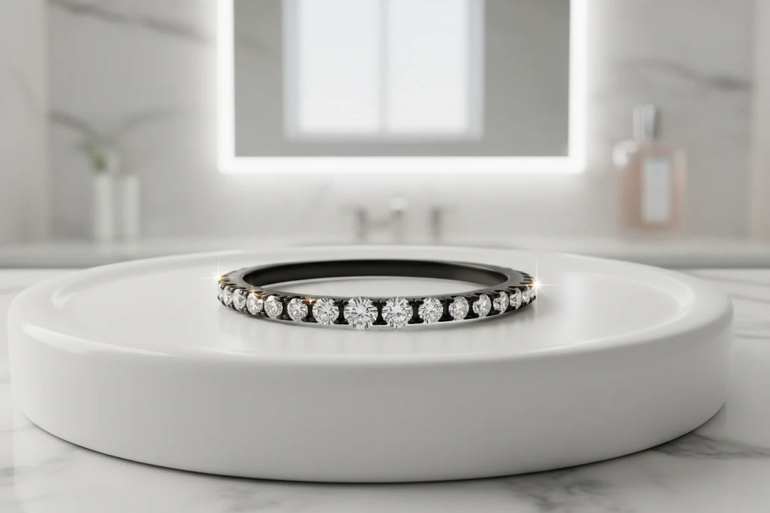 Black Midi Ring Set shown as a slim black band ring with sparkling clear stones, photographed on a white round display platform in a bright bathroom vanity setting with soft reflections and a clean, modern background | OriaJewel