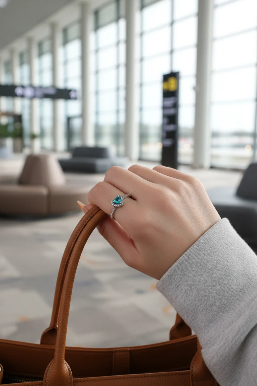 Blue Heart Halo CZ Ring worn on a hand holding a brown leather bag handle in a bright modern terminal setting, highlighting the blue heart halo sparkle on the finger | OriaJewel