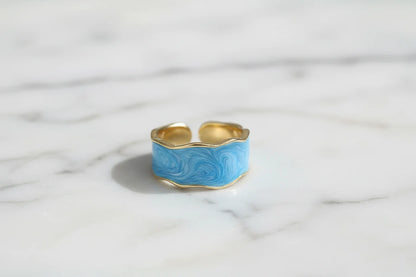 Front view of the Blue Marble Open Wave Ring on white marble surface, showing wavy blue enamel | OriaJewel