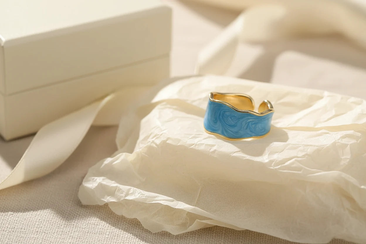 Blue Marble Open Wave Ring styled on crinkled tissue paper with ribbon and gift box nearby | OriaJewel