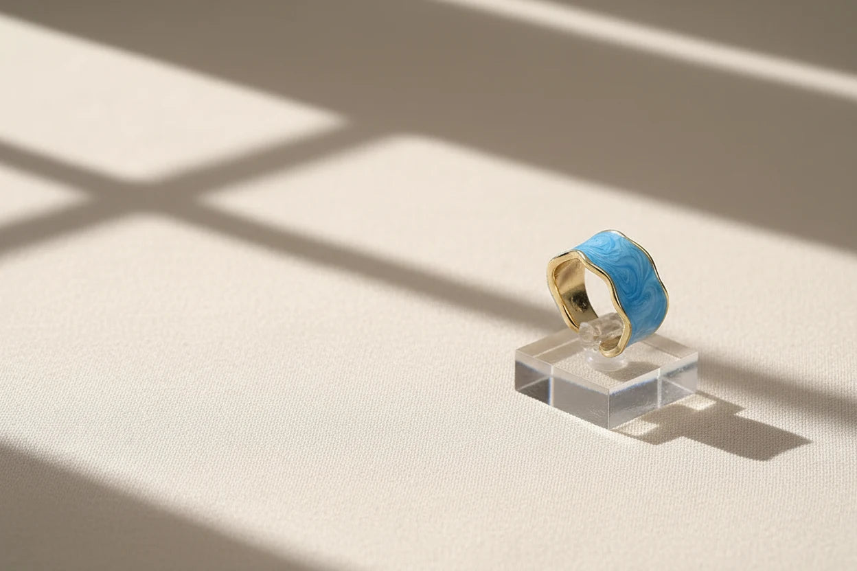 Blue Marble Open Wave Ring displayed on a clear acrylic stand with window-light shadows | OriaJewel