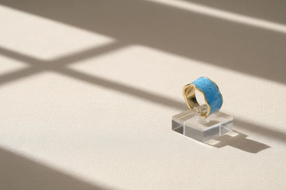 Blue Marble Open Wave Ring displayed on a clear acrylic stand with window-light shadows | OriaJewel