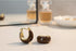 Brown Resin Huggie Hoop Earrings close-up on table with soft-focus perfume background | OriaJewel