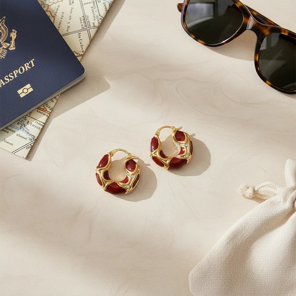 Burgundy Red Huggie Hoop Earrings flat lay with passport, map, sunglasses, and pouch | OriaJewel