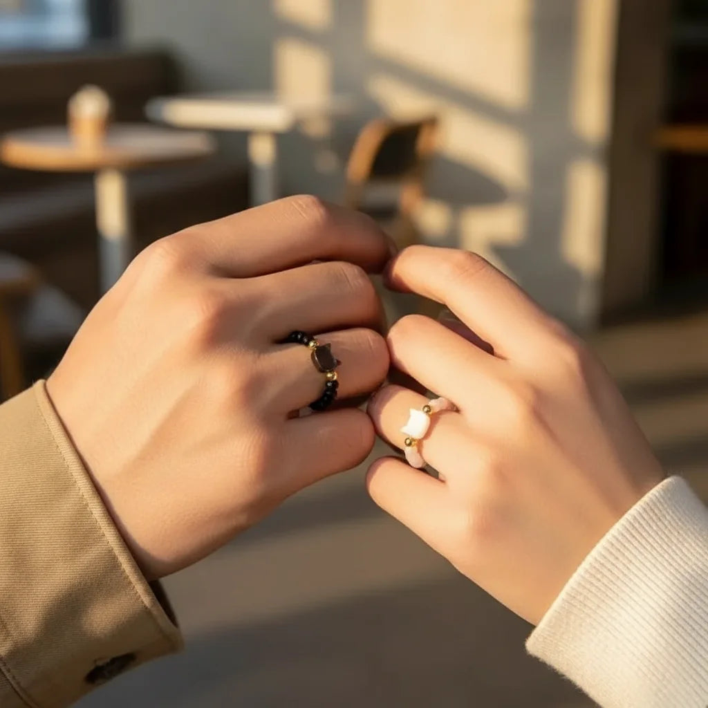 Hands wearing Cat Charm Ring and another ring, showcasing elegant jewelry in a cozy setting | Oria Jewel