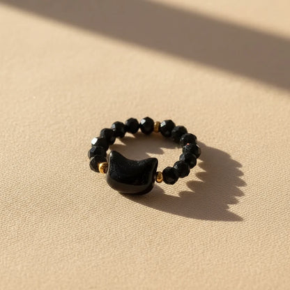 Black faceted bead Cat Charm Ring, gold accents, on sunlit beige | Oria Jewel